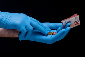 Hand, with a latex glove, holding a euro bill