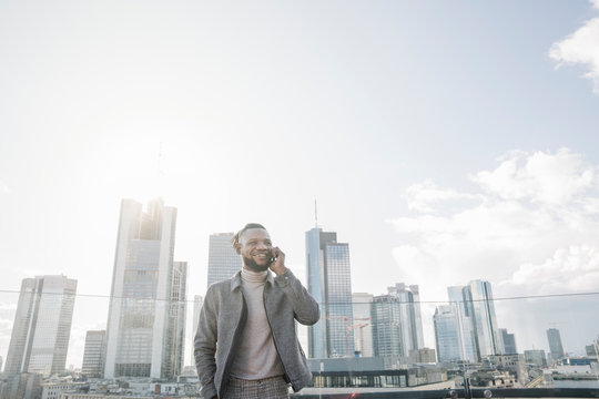 Smiling man on the phone on observation terrace with skycraper view, Frankfurt, Germany