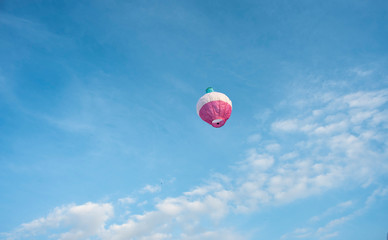  A colorful lantern/balloon is flying in the blue sky with white clouds in the afternoon of Diwali....