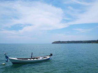 Naklejka na ściany i meble Blue sea and white boat. Panoramic view of azure water surface, beautiful sky with clouds, green cape in a distance, horizon. Conceptual picture of seascape. Panorama of nature. Idea for design. 
