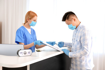 Female receptionist working with patient in clinic