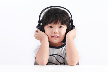 Cute little Asian boy listening to a music in a headphone isolated on white background