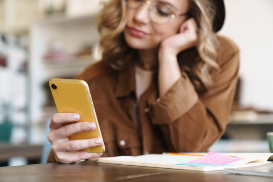 Image of displeased nice woman using cellphone while studying