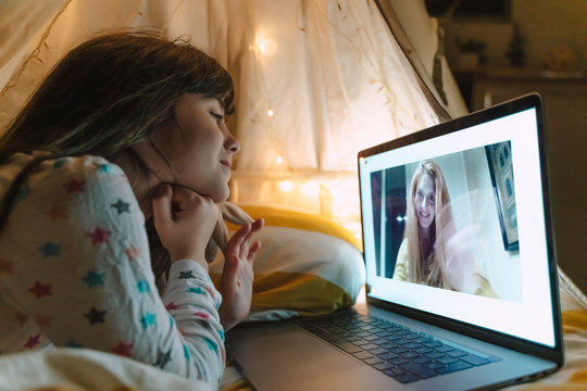 Girl lying on bed at night skyping with her mother working outside home