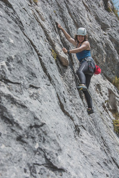 Female mountain climber climbing rock face
