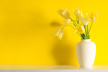 Bouquet yellow tulips in vase on yellow background. Floral yellow background with tulips. Spring flowers. Happy Women's Day, Mother's Day, Valentine's Day, copy space