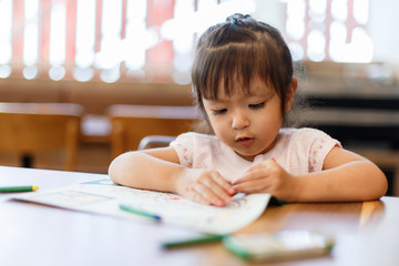 Asian kid girl having fun to draw and paint with crayon