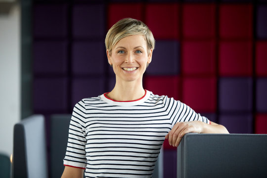 Portrait of a smiling woman at a purple wall
