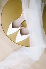 white wedding shoes with accessorieson a golden background.