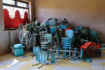 Chairs stacked up in an old school hall
