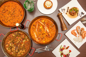 overhead photo of paellas and shrimp dishes