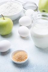 Milk, flour, eggs and green apples on a white background. Ingredients for apple charlotte. Recipe