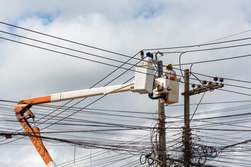 electricians repairing wire of the power line on electric power pole