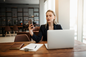 Obraz premium A young girl-Manager, sitting in a coworking office at her workplace in front of a laptop, and talking online via video link