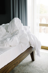Fototapeta na wymiar Large white bed standing in the room. Crumpled sheet and blanket.