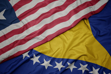 Obraz premium waving colorful flag of bosnia and herzegovina and national flag of liberia.