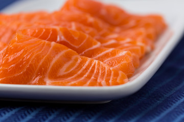 Salmon raw sashimi on whiteJapanese traditional dish on blue tablecloth.