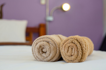 brown towels rolls on bed sheet in the hotel.