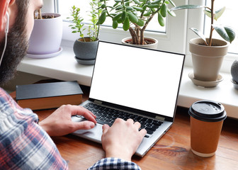 A man in a plaid shirt uses a laptop with a white screen isolated. A blank for placing your information on a computer screen.