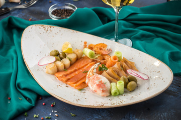 Seafood platter Prawns, Scallops, Salmon, crab claw and white fish woth glass of white wine on turquoise background