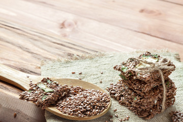 Flat lay top view crunchy flax seed crispbread and linseed spoon on wooden rustic background. Healthy snack: cereal crunchy multigrain cerealflax seed, sesame, raw dry zucchini vegetable. Vegan food