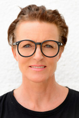 Fototapeta premium Face of beautiful mature woman wearing big eyeglasses and standing against white background outdoors
