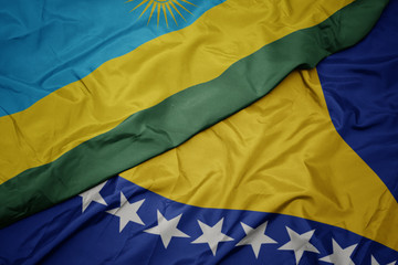 waving colorful flag of bosnia and herzegovina and national flag of rwanda.