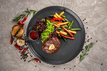 Meat medallion with mushrooms on a round white plate on a dark brown background. restaurant menu