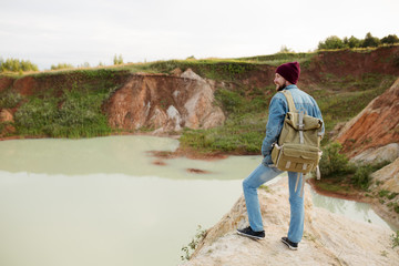 A bearded man stands on a hill, and admires the beautiful landscape and views of the blue lake