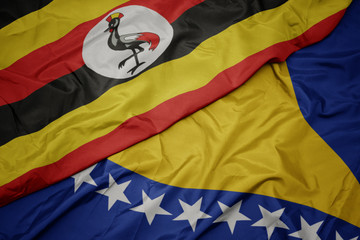 waving colorful flag of bosnia and herzegovina and national flag of uganda.