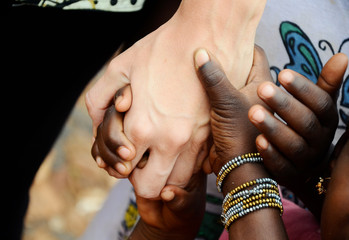 Group of Multiracial Black Children and White Adult Holding Hands Together