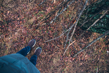 feet in jeans and sneakers on the soil in the forest