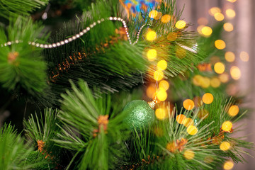 Decorated Christmas tree closeup. Red and golden balls and illuminated garland with flashlights. New Year baubles macro photo with bokeh. Winter holiday light decoration