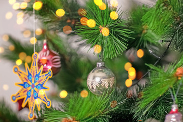 Decorated Christmas tree closeup. Red and golden balls and illuminated garland with flashlights. New Year baubles macro photo with bokeh. Winter holiday light decoration