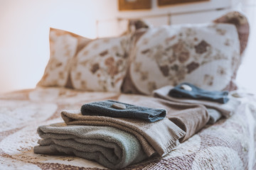 Freshly laundered towels stacked on bed in a guest room of a boutique hotel. Retro style bedroom....
