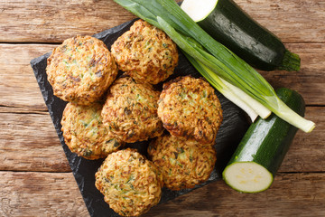 Tasty greek zucchini balls with feta cheese with ingredients close-up on a slate board. Horizontal top view