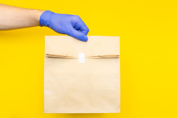 postman with parcel. courier in medical gloves holding paper craft bag with food, supplies from...