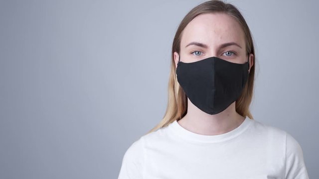 Woman in a black medical mask, isolated on a gray background