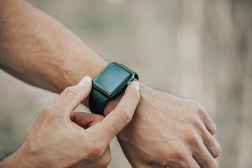 Macro concept of man clicking, pointing on a screen of his generic design smart watch, blurred background