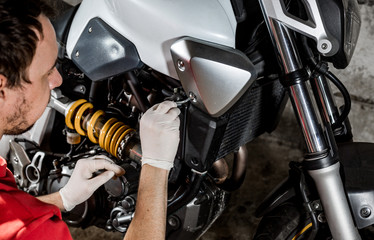 Obraz premium Mechanic repairman doing maintenance or repairing, fixing on the motorcycle, motorbike, service center