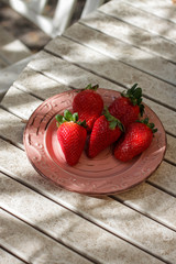 Harvest strawberry on a white wooden table in the garden close up.