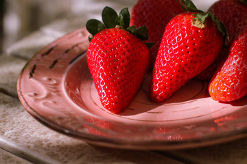 Harvest strawberry on a white wooden table in the garden close up.