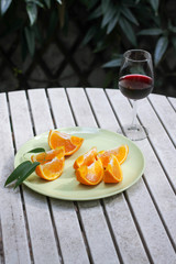 Red wine served outside in garden on white table with fresh orange in sun lights close up