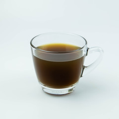 Glass cup of hot ginger tea isolated on white background.