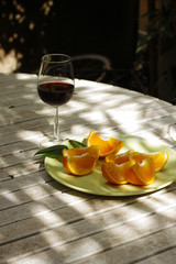 Red wine served outside in garden on white table with fresh orange in sun lights close up