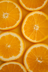 Round fresh orange slices, summer yellow background.
