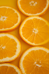 Round fresh orange slices, summer yellow background.