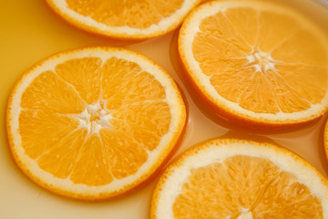Round fresh orange slices, summer yellow background.