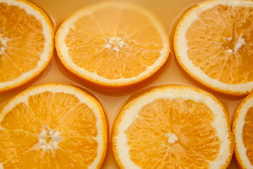 Round fresh orange wet slices, summer yellow background.