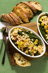Cannellini nutritious white bean salad with green beans, sun-dried tomatoes and artichokes in oil. Traditional italian food